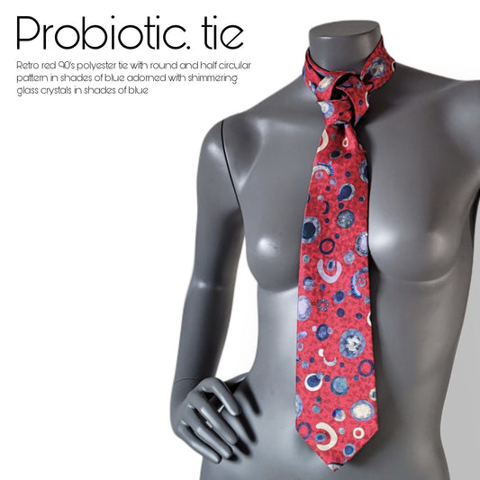 Another Dance collection: Probiotic. tie, retro 90's polyester necktie in red with round and half circular pattern in shades of blue, adorned with shimmering blue glass crystals