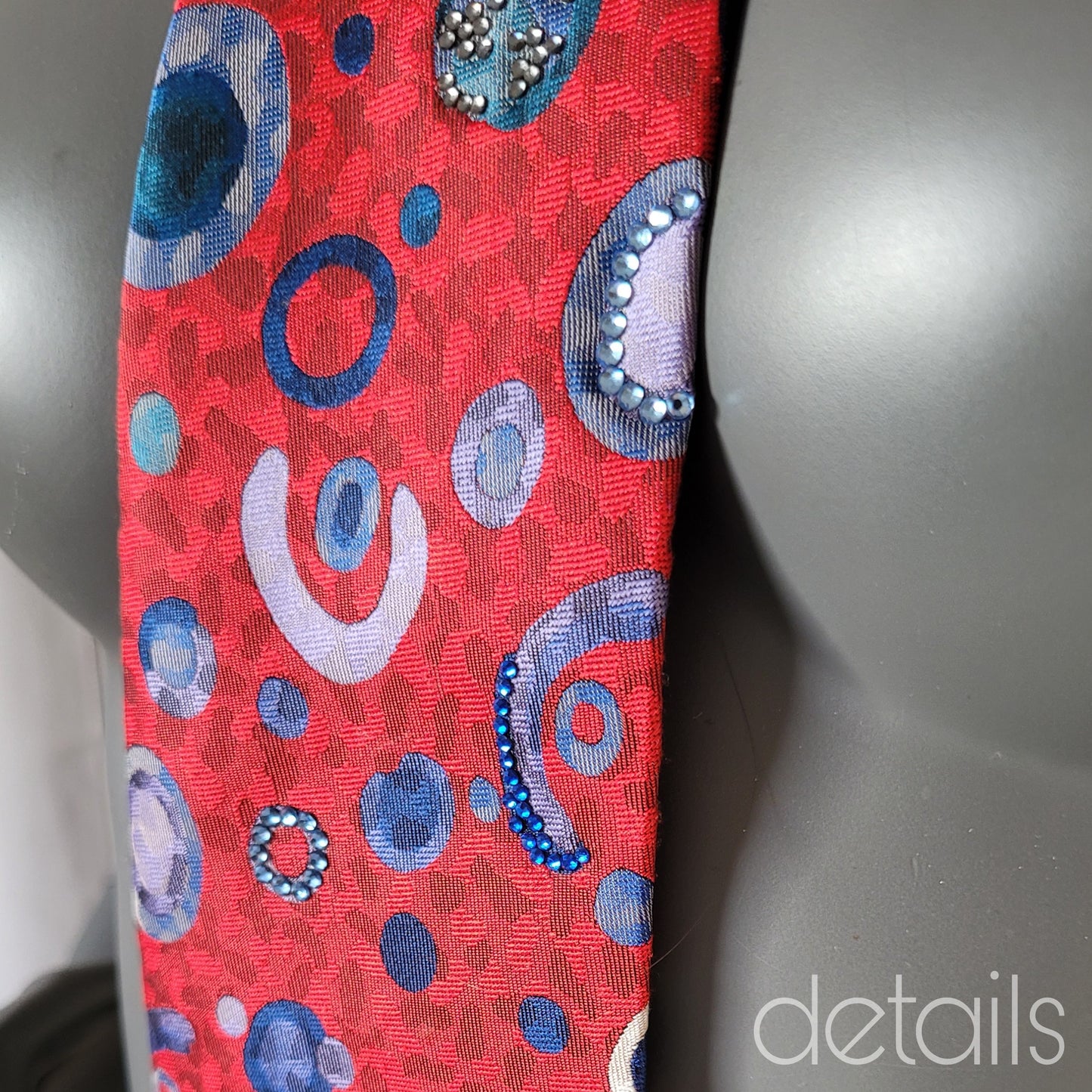 Another Dance collection: Probiotic. tie, retro 90's polyester necktie in red with round and half circular pattern in shades of blue, adorned with shimmering blue glass crystals